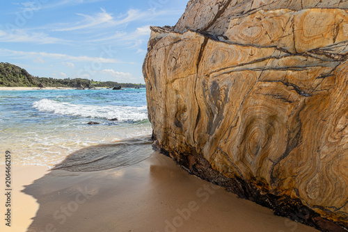A large metamorphic rock, deformed by heat and pressure from volcanic activity, seen here on the beach in close up to reveal the chevron patterns so formed at Narooma in New South Wales, Australia.