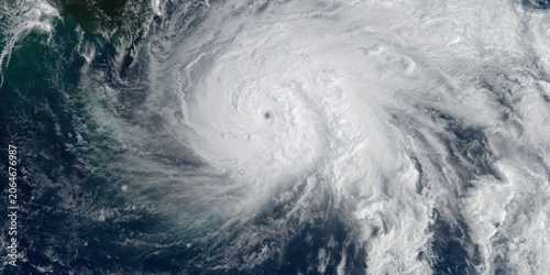 Satellite view of a powerful tropical cyclone swirling over the ocean with a clear eye and dense white cloud bands