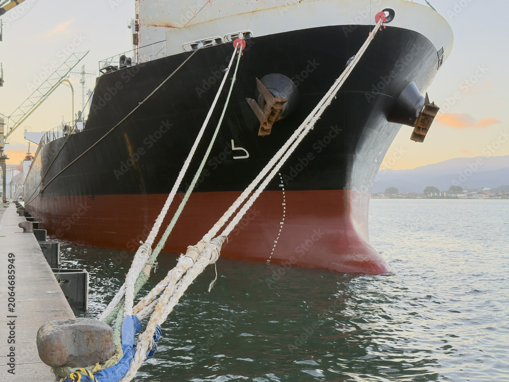 Naklejka premium bulk carrier vessel moored in port. ship bow and bulb. mooring lines and anchors.