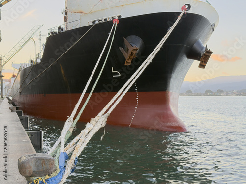 bulk carrier vessel moored in port. ship bow and bulb. mooring lines and anchors.