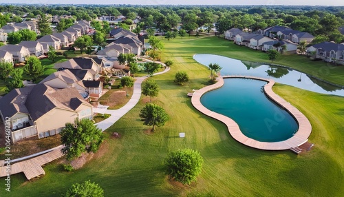lush green community rheudasil park in flower mound texas with curved boardwalk walking trails playground upscale suburban two story houses with resort style swimming pool grassy lawn aerial