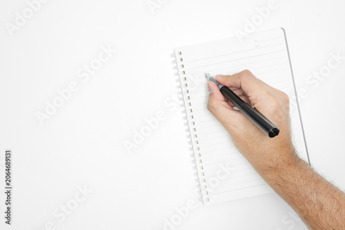 Top view of a male hand writing with a black fountain pen in a blank spiral notebook isolated on a white background with copy space