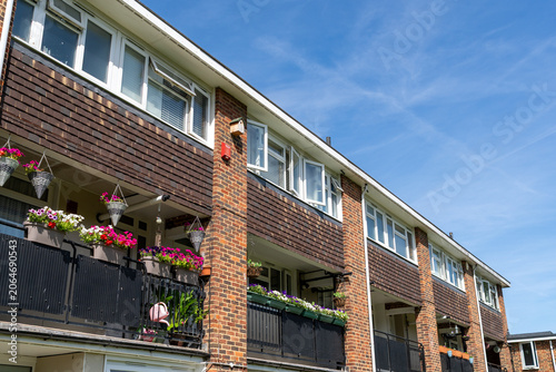 Billede på lærred Row of modern residential apartments with balconies flower pots and clear blue s