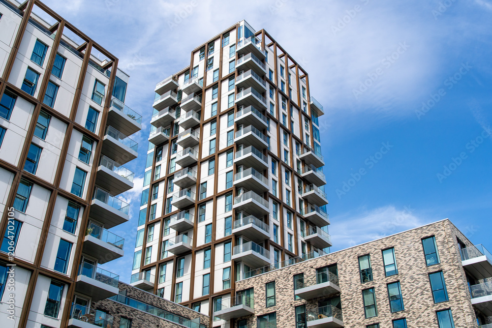 Fototapeta premium Modern residential apartment buildings with glass balconies under blue sky urban architecture