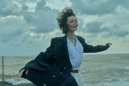 Foto Wind, beach, coat, business attire set the scene for a confident, free moment by the ocean, with windblown movement and outdoor breeze