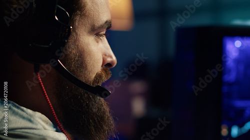 Фотография Pro gamer at home talking with teammates, competing together in intense online multiplayer video game, extreme close-up, man having gaming session with friends, using powerful computer to play game