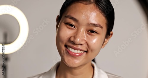 Young Asian woman showing fresh skin and smiling in studio portrait