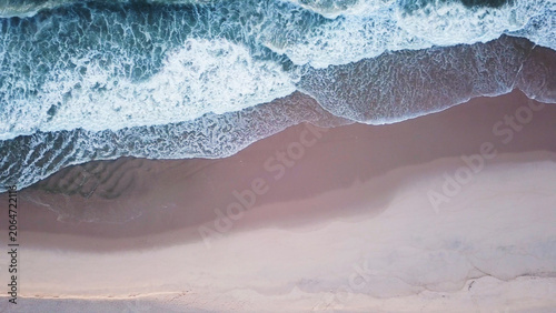 Aerial view of ocean waves hitting a sandy beach