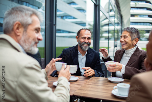 Older friends laughing over coffee at outdoor cafe
