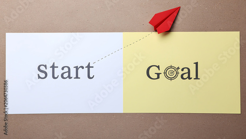 Red paper airplane flies from start to goal on contrasting paper sheets with brown background