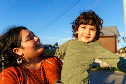 Canvas Print Hispanic mother holding smiling toddler outdoors.