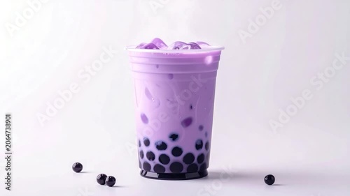 A close-up of a clear plastic cup filled with taro bubble tea, ice cubes, and black tapioca pearls