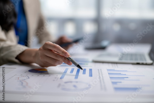 Business person analyzing financial report charts with pen