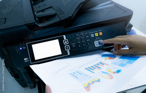Obraz na plátne Office worker prints paper on multifunction laser printer
