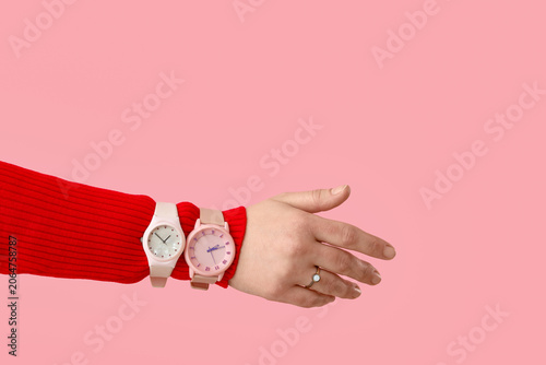 Female hand with stylish wristwatches on pink background