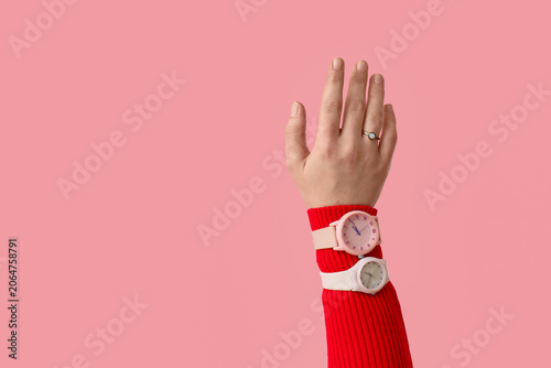 Female hand with stylish wristwatches on pink background