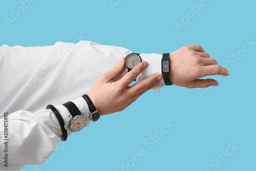 Female hands with different stylish wristwatches on blue background