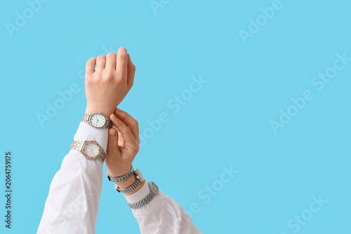 Female hands with different stylish wristwatches on blue background