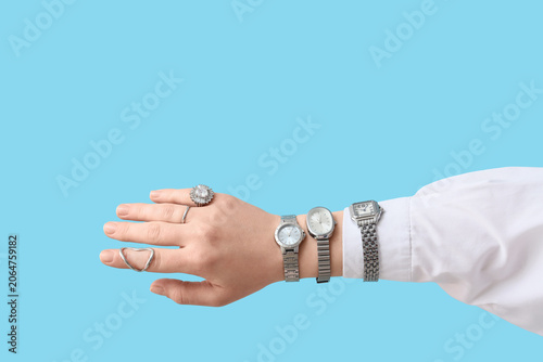 Female hand with different stylish wristwatches on blue background
