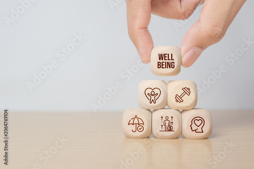 Employee wellbeing concept. Hand hold wooden blocks with physical, mental, emotional health icons. Creating employee benefits. Fostering positive work culture, employee engagement