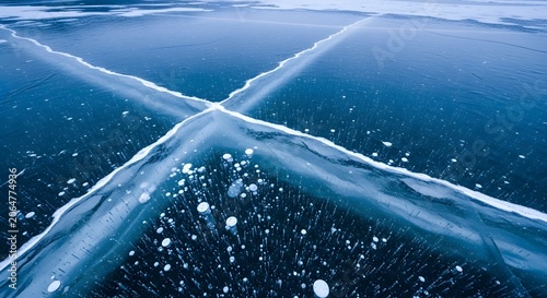 Stunning frozen lake surface with deep blue ice cracks and trapped air bubbles