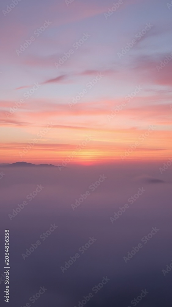 Obraz premium Pink and purple hues of sunset above foggy valley