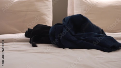Dark clothing casually placed on a neatly made bed in a hotel or bedroom. Concept of travel, accommodation, relaxation, daily routine, personal belongings, and comfortable living space.