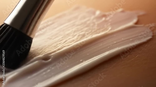Close up of a makeup brush applying foundation on skin.