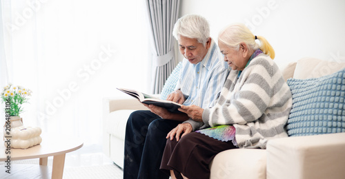 Картината върху платно Senior couple reading books together on a sofa at home