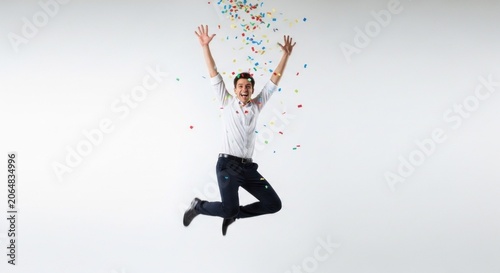 A man jumping in the air with colorful confetti falling around him.