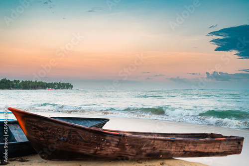 Traditional wooden fishing boats on a tropical beach at sunset.