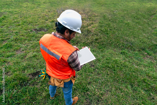 Professional contractor reviewing project plans on a tablet mockup device at a building site