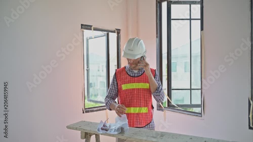 Professional Male Contractor Talk On Mobile Phone At House Construction Site