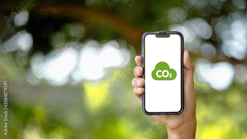 Hand Holding Smartphone with Green CO2 Icon on Screen Stock Photo