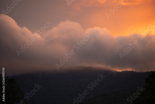 Dramatic fire-colored clouds lighting up the sky above the Blue Ridge Mountains, casting warm tones over the rolling Appalachian landscape at sunset.