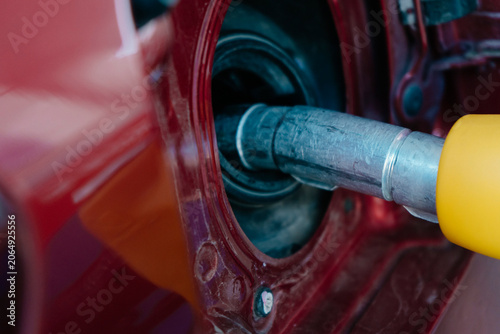 Close-Up of Fuel Pump Inserting Fuel Nozzle into Vehicle Gas Tank, Illustrating the Process of Refueling a Car with Gasoline
