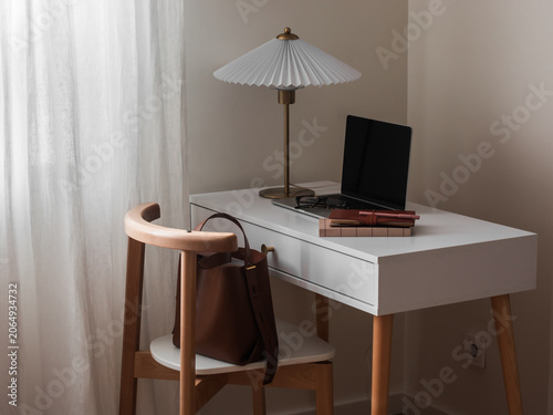 Desktop with laptop, desk lamp, leather bag, notebook in the living room