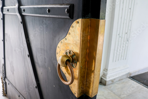 Obraz na plátně Old brass door handle gleams against dark wood