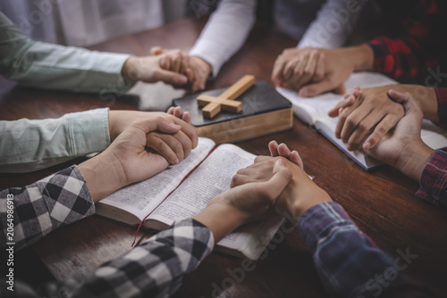 Fotografie Believers holding hands in prayer during Bible study