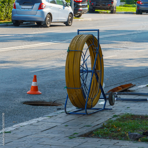 Fiber optic cable reel near open manhole on city street