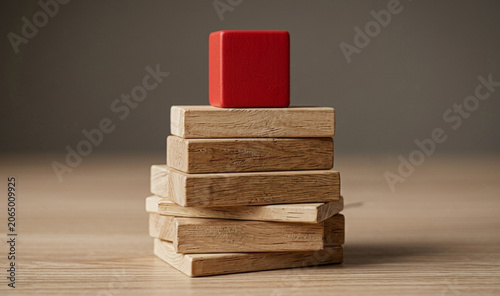 A red cube on top of a stacked wooden block tower