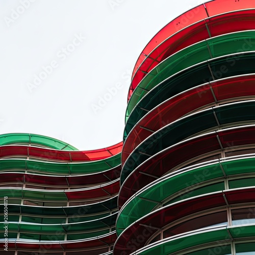Modern Architectural Facade with Wavy Red and Green Panels Against a Bright Sky.