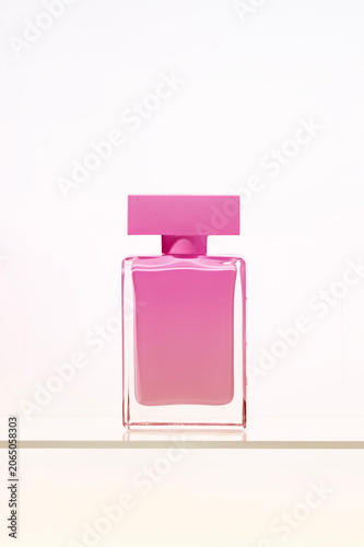 A striking, abstract , colorful perfume bottle. The bold pink liquid and geometric cap stand out on a glass surface, a clean and modern study of luxury and beauty product design.