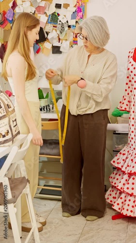 Senior tailor teaching an apprentice how to measure a dress