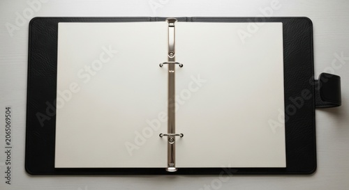 A black binder with blank white pages lies open on a surface.