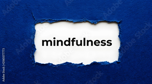 Torn blue paper reveals the word mindfulness in black text ripped white