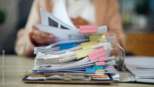 Photography Person holds documents amid a towering stack of papers