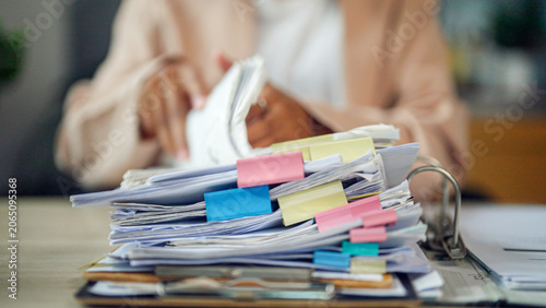 Bild auf Leinwand Person sits at desk, overwhelmed by paperwork