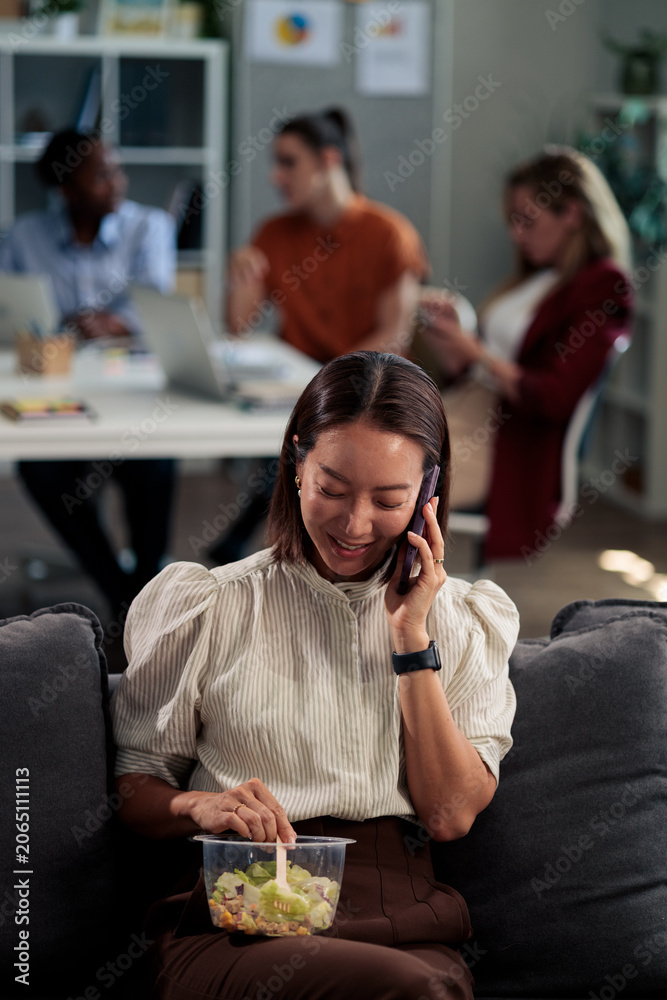 Obraz premium Businesswoman multitasking having healthy office lunch while talking on phone