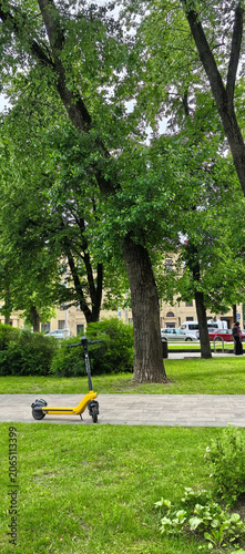 Yellow electric scooter parked on pathway in park
